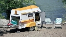 American Dream Trailer z łódką na dachu, która dzięki aerodynamicznym kształtom zmniejsza opory powietrza podczas transportu. Z tyłu przyczepy znajduje się luk bagażowy, a ze ściany możemy zrobić stolik - zdjęcie 8