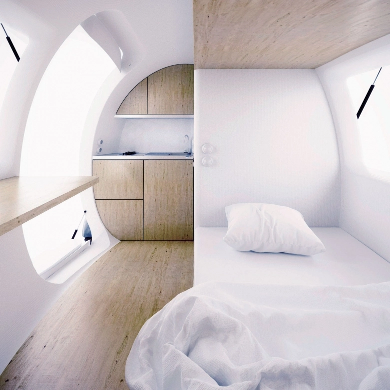 Wnętrze przyczepy. Po lewej stronie – drzwi wejściowe, po prawej łóżko (na pierwszym planie), za którym znajduje się toaleta i prysznic. - zdjęcie 2