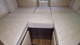 W tylnej części mamy 2 pojedyncze łóżka lub jedno duże, jak na zdjęciu. Pod lewym łóżkiem jest szafa na odzież - zdjęcie 5